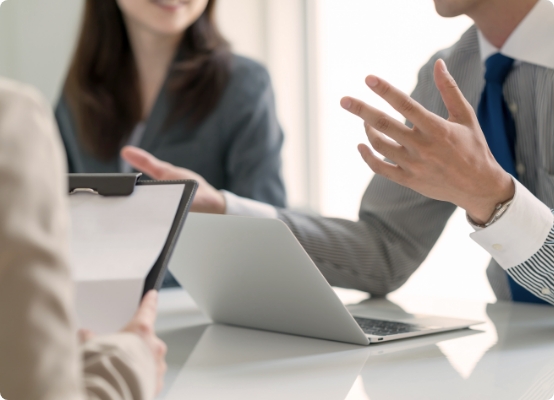 ノートパソコンを前に打ち合わせを行うビジネスパーソン