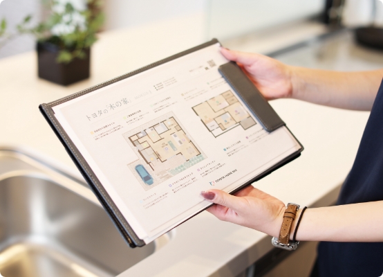 住宅プランの資料を手に持ち説明する担当者