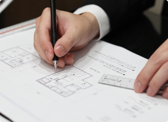建築設計図にペンで描き込みをする設計士の手元