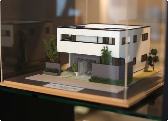 モダンな外観の住宅模型がケース内に展示されている様子