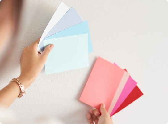 壁の前で色見本カードを見比べるインテリアコーディネーター