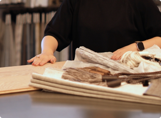 テーブルに広げた生地や素材サンプルを確認するインテリアコーディネーター