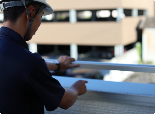 建物の外壁部分を指差して確認する施工管理スタッフ